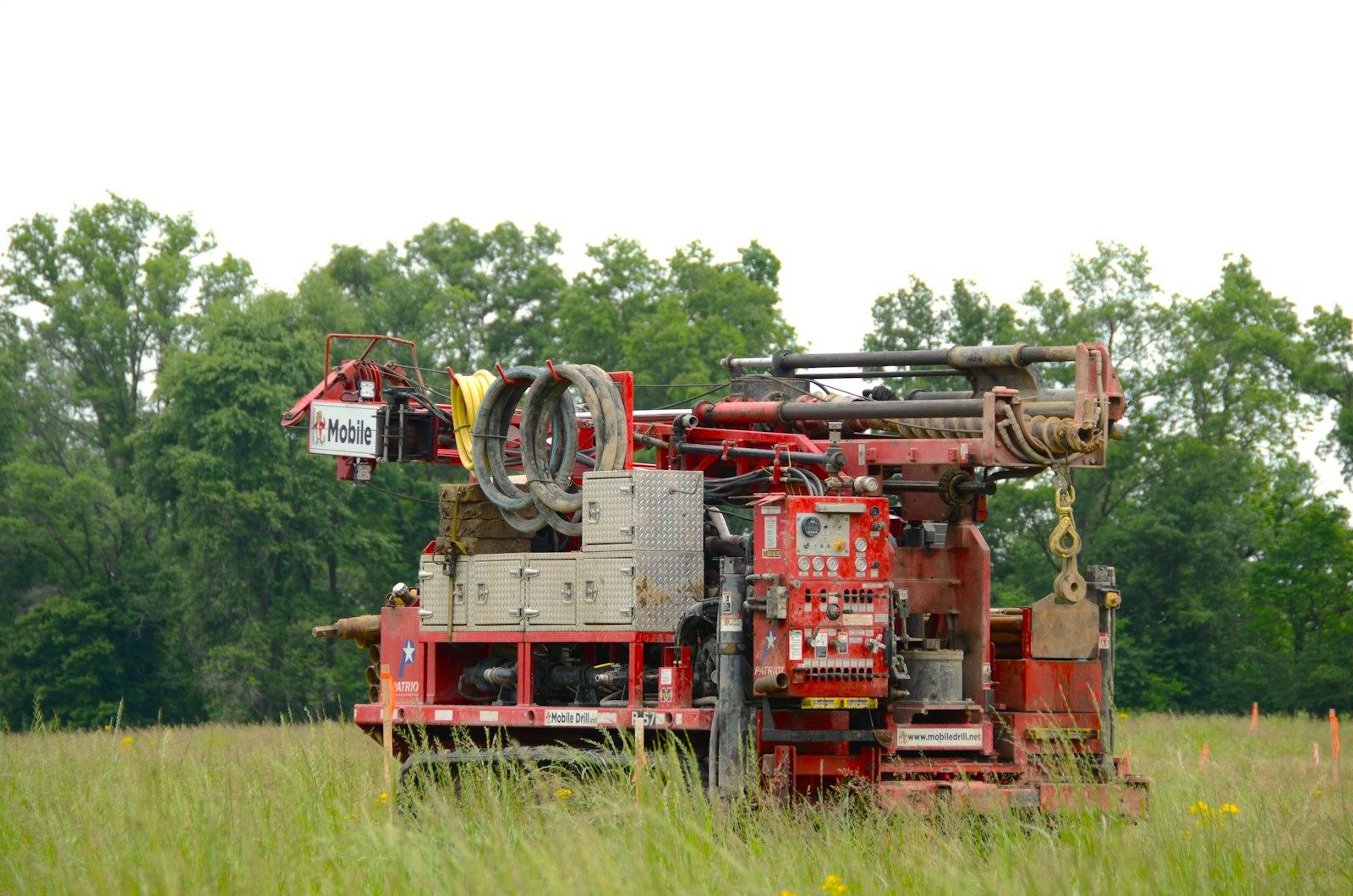 A track-mounted rotary drill rig with hoses and a mast